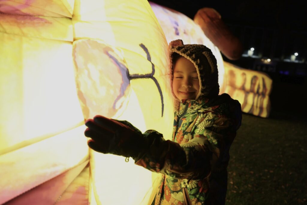 A child hugging a giant cat artwork as part of Shine on, Boro.